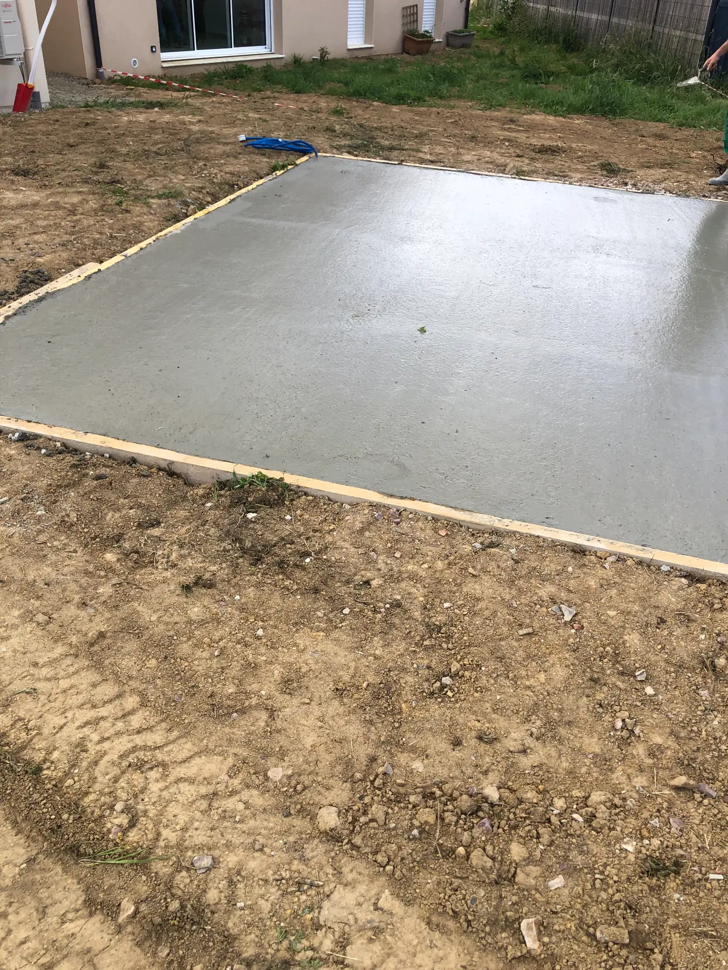 Dalle béton fraîchement coulée et lissée dans son coffrage de bois